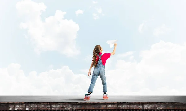 可爱的小女孩在楼顶上玩纸飞机 — 图库照片