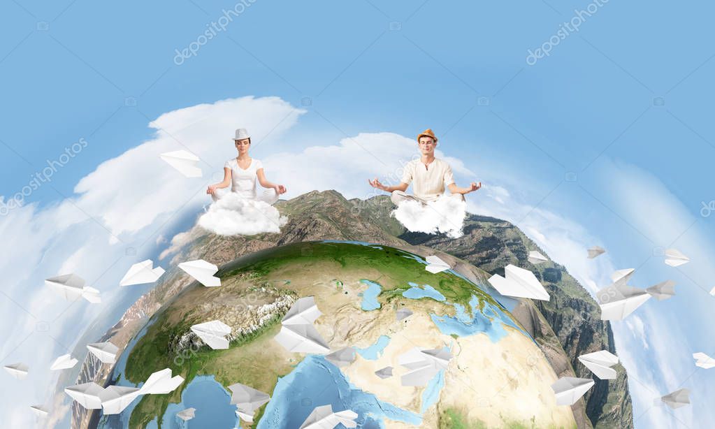 Young couple keeping eyes closed and looking concentrated while meditating on clouds in the air with panoramic view of Earth globe on background. Elements of this image are furnished by NASA