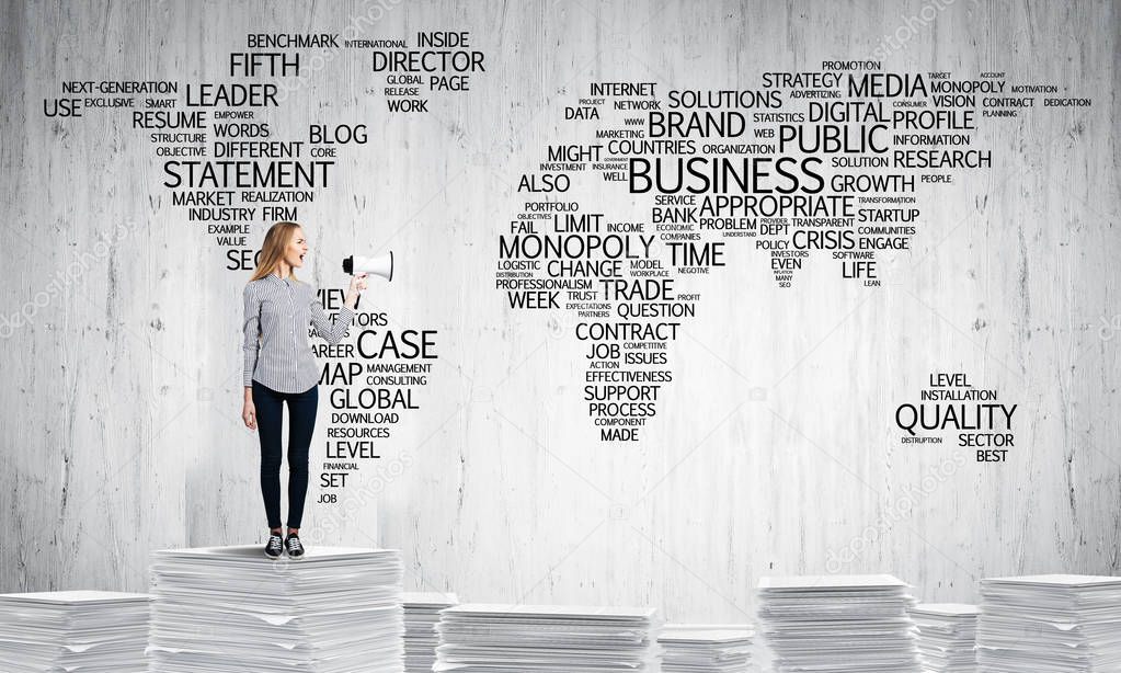 Woman in casual wear standing on pile of documents with speaker in hand with business-related terms in form of world map on background. Mixed media.