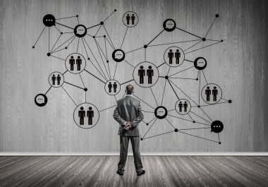 Arkadan görünüşü çizilmiş sosyal bağlantı kavramı ile duvara bakarak işadamı