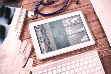 Beyaz tablet bilgisayar ve doktor aletleri ahşap masada.