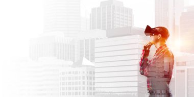 Sanal gerçeklik kulaklığı olan genç bir adam ya da şehrin arka planında 3 boyutlu gözlüklü.