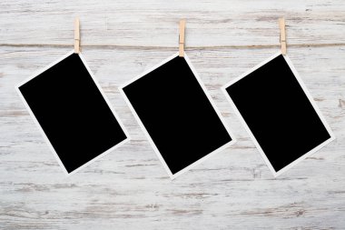 Boş fotoğraf çerçevesi ahşap bir zeminde ipte asılı.