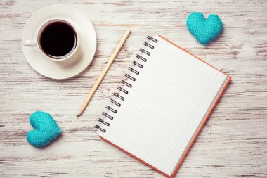 Kahve fincanı not defteri kalem ve ahşap yüzeyde iki kalp
