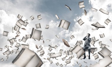 Genç yığın kitap üzerinde oturan ve avuç içi gözlerle kapsayan bir işadamı şok