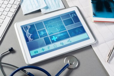 Gri yüzeyde beyaz tablet ve doktor araçları