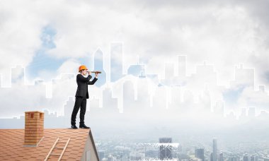 Takım elbiseli genç işadamı ve çatıda kask var. Karışık ortam