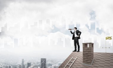 Çatıda takım elbiseli genç bir işadamı var. Karışık ortam