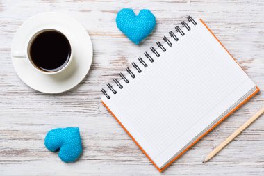 Kahve fincanı not defteri kalem ve ahşap yüzeyde iki kalp