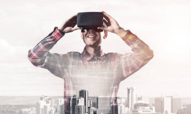 Sanal gerçeklik kulaklığı olan genç bir adam ya da şehrin arka planında 3 boyutlu gözlüklü.