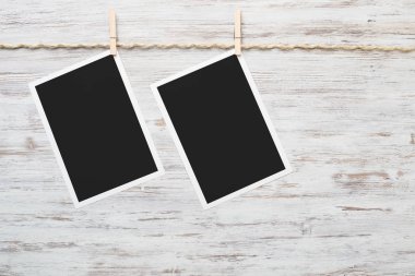 Boş fotoğraf çerçevesi ahşap bir zeminde ipte asılı.