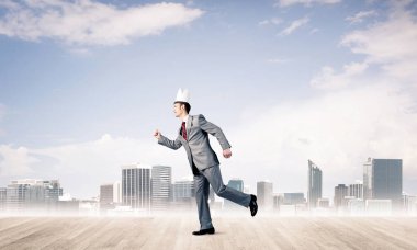 Beyaz taçlı yakışıklı iş adamı aceleyle koşuyor.