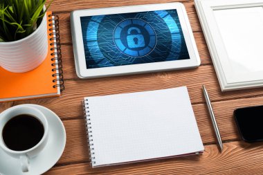 Ofis eşyalarıyla iş yeri ve ekranda asma kilit simgeleri olan tablet