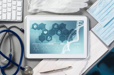 Gri yüzeyde beyaz tablet ve doktor araçları