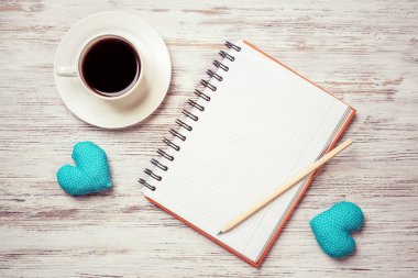 Kahve fincanı not defteri kalem ve ahşap yüzeyde iki kalp