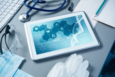 Gri yüzeyde beyaz tablet ve doktor araçları