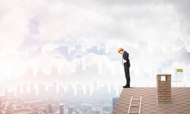 Takım elbiseli genç işadamı ve çatıda kask var. Karışık ortam