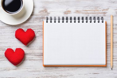 Kahve fincanı not defteri kalem ve ahşap yüzeyde iki kırmızı kalp