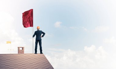 Çatıda duran ve elinde kırmızı bayrak tutan bir iş adamı. Karışık ortam