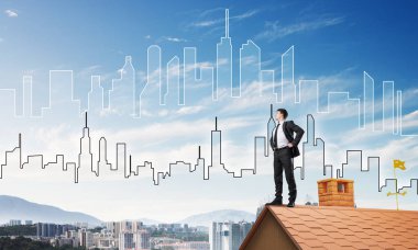 Kararlı genç işadamı evin çatısında dikiliyor ve başka tarafa bakıyor. Karışık ortam