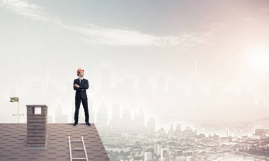 Takım elbiseli genç işadamı ve çatıda kask var. Karışık ortam