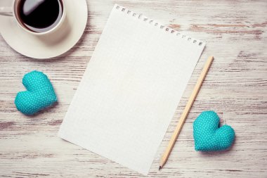 Kahve fincanı not defteri kalem ve ahşap yüzeyde iki kalp