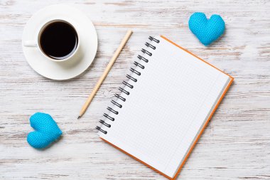 Kahve fincanı not defteri kalem ve ahşap yüzeyde iki kalp