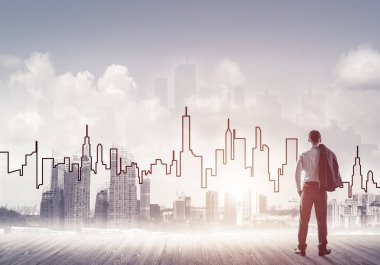 İşadamı arkasını dönüp modern iş merkezinin siluetine bakıyor.