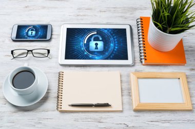 Ofis eşyalarıyla iş yeri ve ekranda asma kilit simgeleri olan tablet