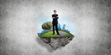 Yeşil yüzen adada beton zemine karşı duran kendine güvenen zarif iş adamı.