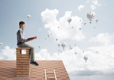 Elinde kırmızı kitap ile evin baca rahat oturan genç adam