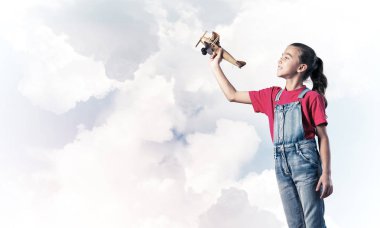 Elinde retro uçak modeliyle tulumlu şirin bir kız çocuğu.