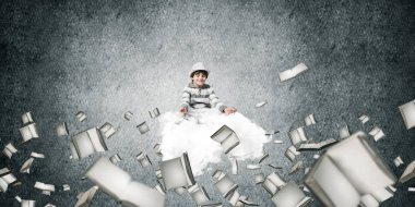 Genç küçük çocuk gözleri koruma kapalı ve seyir üzerinde uçan bulut kitaplar ile gri karanlık duvar arka plan üzerinde uçan arasında meditasyon sırasında konsantre.