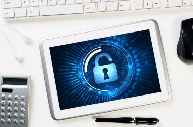 Ofis eşyalarıyla iş yeri ve ekranda asma kilit simgesi olan tablet