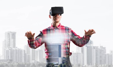 Sanal gerçeklik kulaklığı olan genç bir adam ya da şehrin arka planında 3 boyutlu gözlüklü.