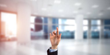 İş kadınının eli ekranda kapalı, arka planda parmak ve ofis var.