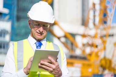 Kıdemli mühendis erkek takım elbise ve tablet PC'de çalışma kask