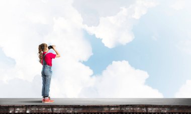 Dürbünle bakan, okul çağındaki sevimli kız çatıyı inşa ediyor.