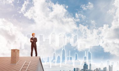 Takım elbiseli genç işadamı ve çatıda kask var. Karışık ortam