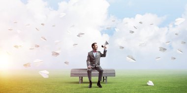 Genç işadamı bankta oturuyor ve duygusal olarak megafonla bağırıyor