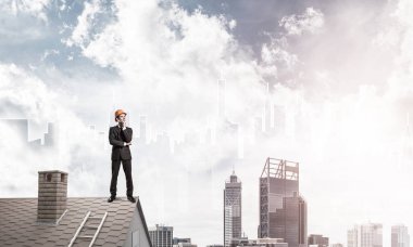 Takım elbiseli genç işadamı ve çatıda kask var. Karışık ortam