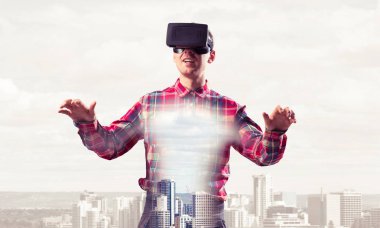 Sanal gerçeklik kulaklığı olan genç bir adam ya da şehrin arka planında 3 boyutlu gözlüklü.