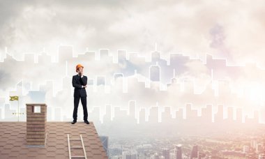 Takım elbiseli genç işadamı ve çatıda kask var. Karışık ortam