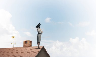 Evin çatısında baş durmak yerine kamerayla zum yapan yüzsüz iş kadını.