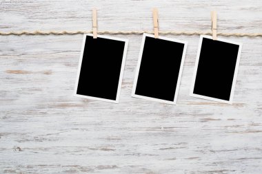 Boş fotoğraf çerçevesi ahşap bir zeminde ipte asılı.