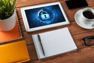 Ofis eşyalarıyla iş yeri ve ekranda asma kilit simgeleri olan tablet