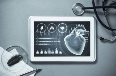 Gri yüzeyde beyaz tablet ve doktor araçları