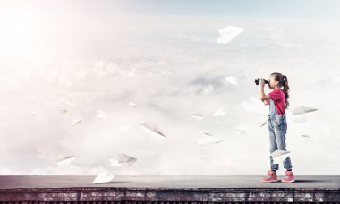 Dürbünle bakan, okul çağındaki sevimli kız çatıyı inşa ediyor.