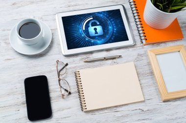 Ofis eşyalarıyla iş yeri ve ekranda asma kilit simgeleri olan tablet