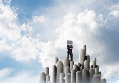 Arka plan üzerinde duran güzel gökyüzü ile taş sütun üst dizüstü bilgisayar kafasına silah tutmak yerine ile takım elbiseli işadamı geçti.